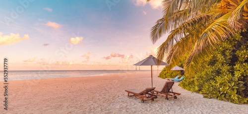 Fototapeta Naklejka Na Ścianę i Meble -  Beautiful panoramic paradise tropical beach sunset as summer island landscape with beds umbrella palm leaves calm sea shore coast. Luxury travel panorama couple destination banner for vacation holiday