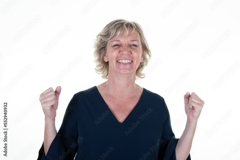 Middle age caucasian smiling senior blonde woman with clenched fists gesture in up air happy on white background Middle age caucasian smiling senior blonde woman with clenched fists gesture in up air happy on white background
