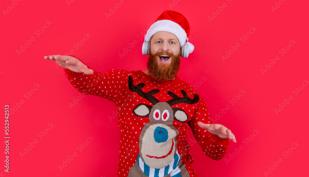 Bearded man celebrating Christmas listening to music. Happy Santa Claus singing and dancing to music