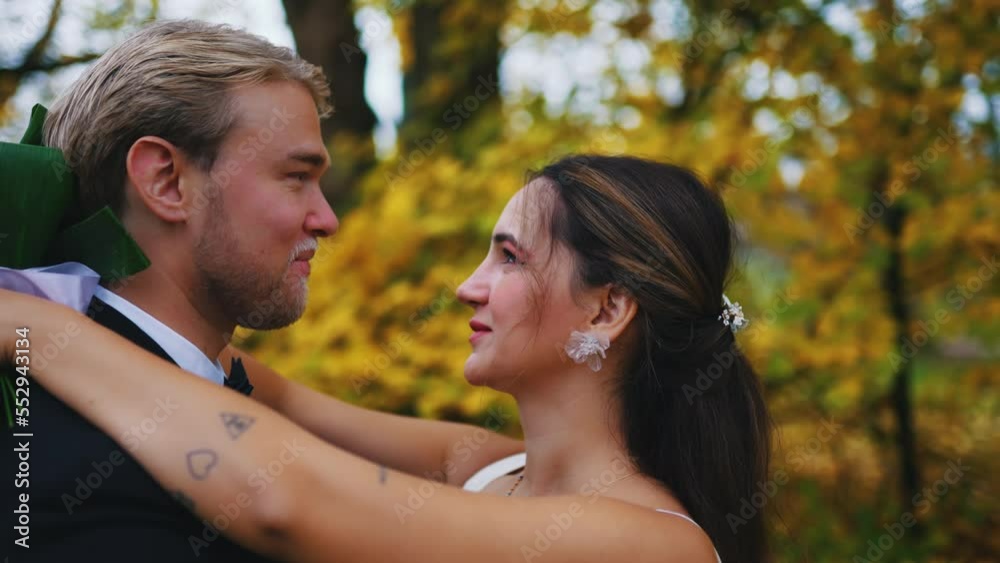Happy newlywed heterosexual couple in wedding clothing standing in autumn forest or park during post-wedding photoshoot. Love and marriage. Medium outdoor shot. High quality 4k footage Happy newlywed heterosexual couple in wedding clothing standing in autumn forest or park during post-wedding photoshoot. Love and marriage. Medium outdoor shot. High quality 4k footage