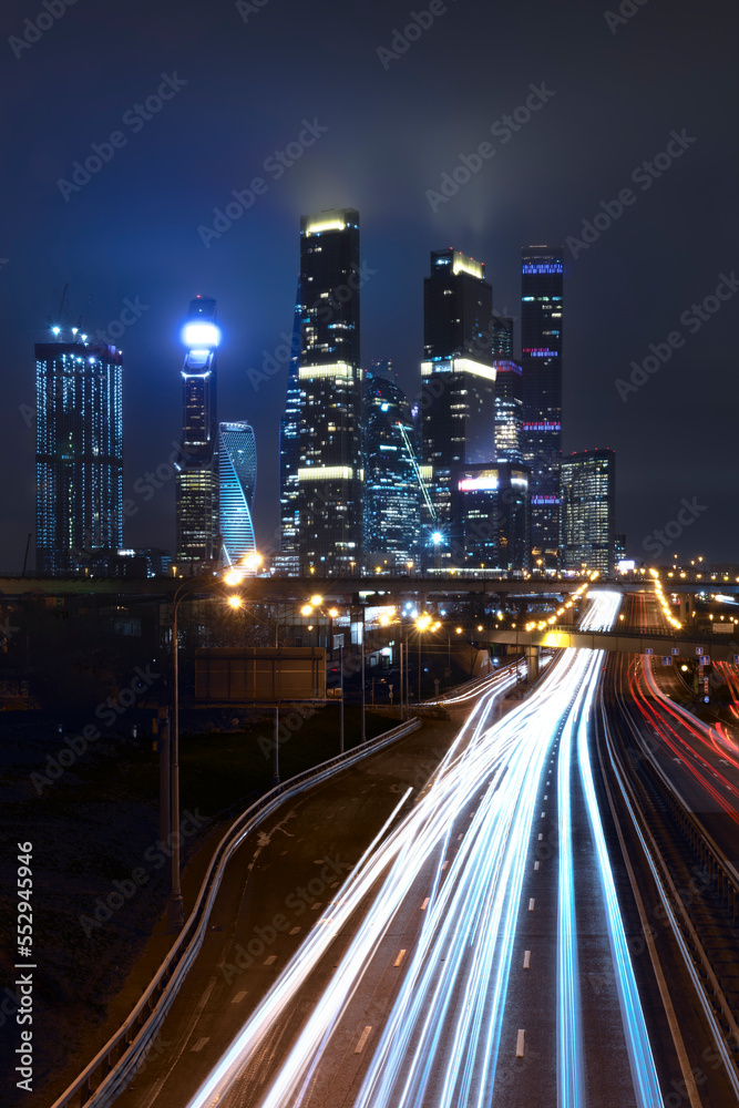 View of the towers of the night city, light tracks of moving cars