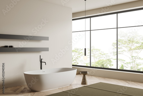 Beige bathroom interior with bathtub and accessories, panoramic window