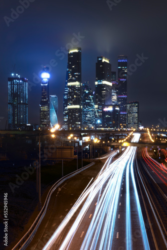 View of the towers of the night city, light tracks of moving cars © Elza_R