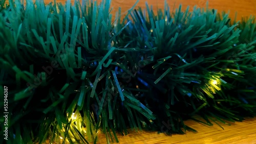 shimmering christmas garlands wrapped in green tinsel on a wooden background