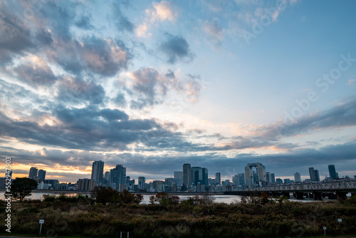 View of a park with buildings and a bridge in the background during sunrise