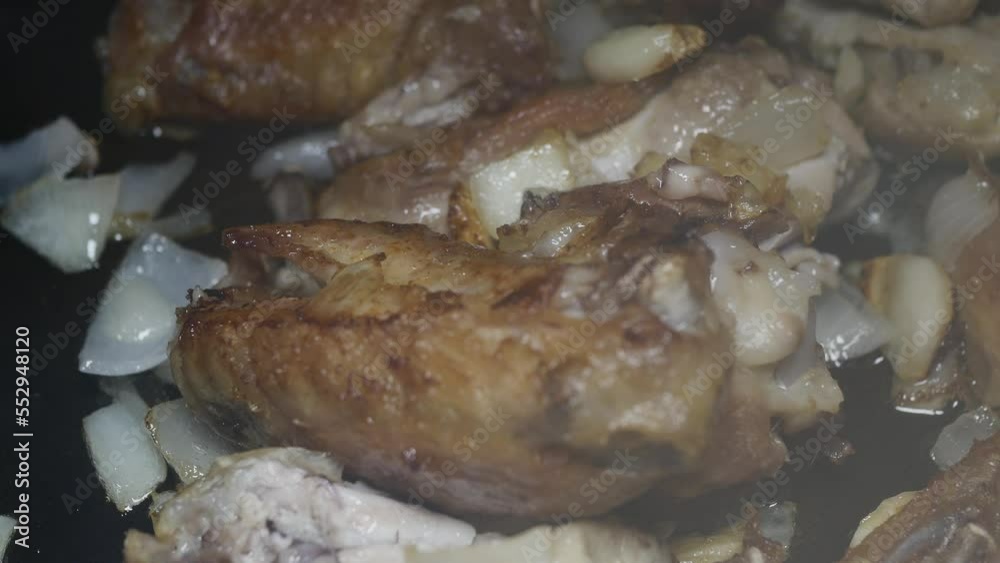 adding ketchup to chicken wings with chopped onion and garlic fried in a pan, macro adding ketchup to chicken wings with chopped onion and garlic fried in a pan, macro