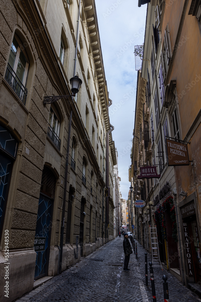 Man walking on a narrow cobblestone street, Rome, Italy
