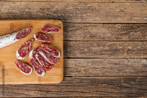 Fuet, typical Catalan sausage spread throughout Spain based on pork and bacon, cut into slices on a wooden cutting board, top view.