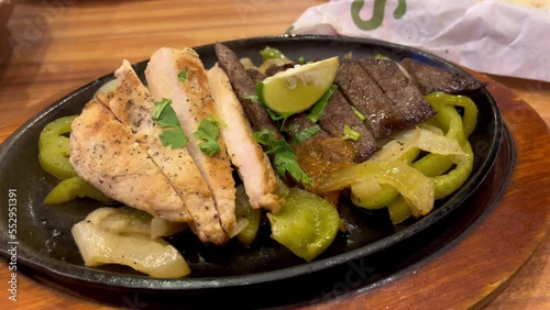 Closed up footage of grilled chicken and beef on a cast iron plate