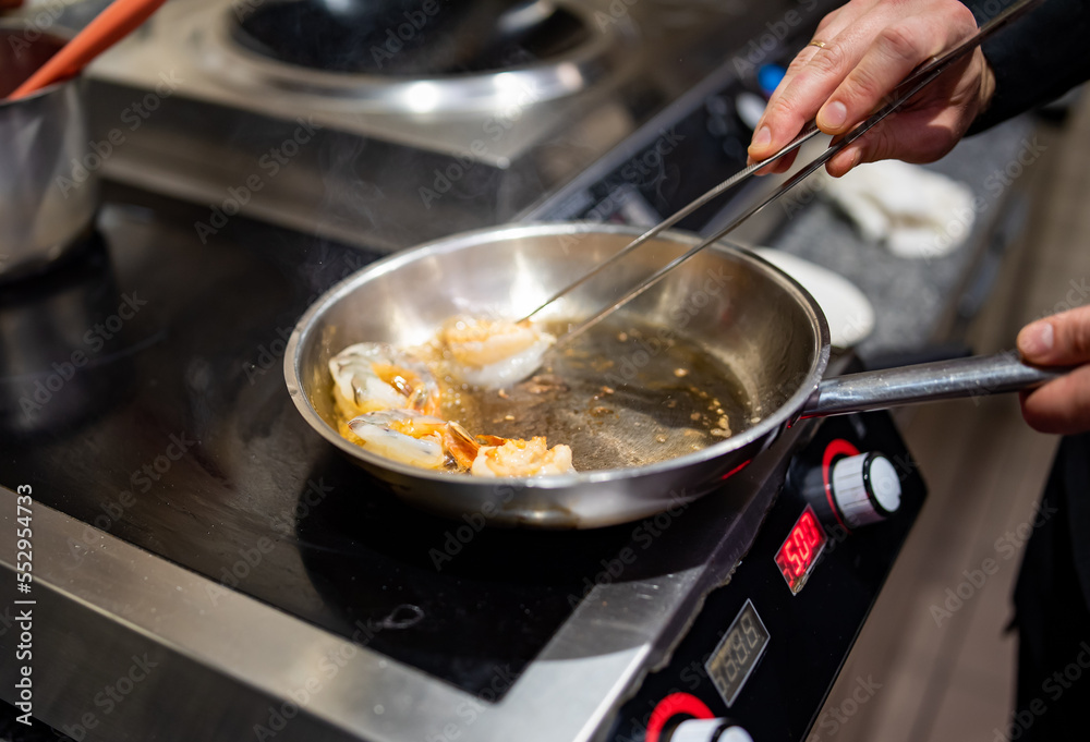man chef cooking tasty shrimp in frying pan on kitchen man chef cooking tasty shrimp in frying pan on kitchen