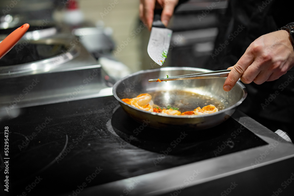 man chef cooking tasty shrimp in frying pan on kitchen man chef cooking tasty shrimp in frying pan on kitchen