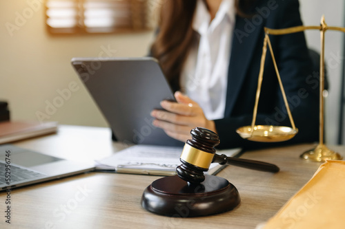 Male lawyer in the office with brass scale and using tablet and laptop on wooden table. justice and law concept