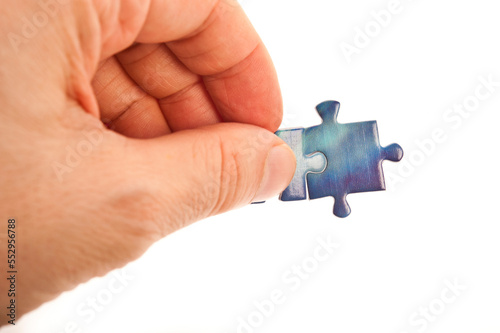 hand connecting two jigsaw puzzle pieces, isolated