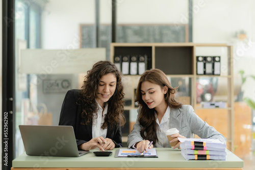 Wallpaper Mural Young attractive caucasian boss and assistant listening financial business consulting with graph paper and tablet laptop on table in office Torontodigital.ca