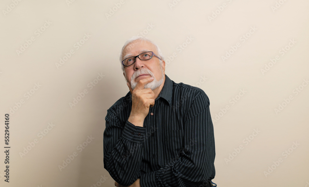 Elderly man in glasses sitting thoughtfully on light background, looking up, eternal question concept, place for text Elderly man in glasses sitting thoughtfully on light background, looking up, eternal question concept, place for text