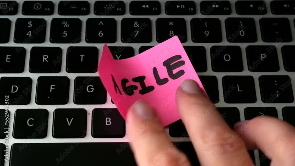 laptop keyboard and hand puts papaer arrow with agile title, software scrum agile board with paper task, concept