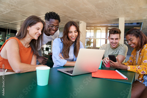 фотографія Group of students, high school pupils gather in college cafeteria, discuss topics, work together on creative task, prepare for university test or exams use laptop