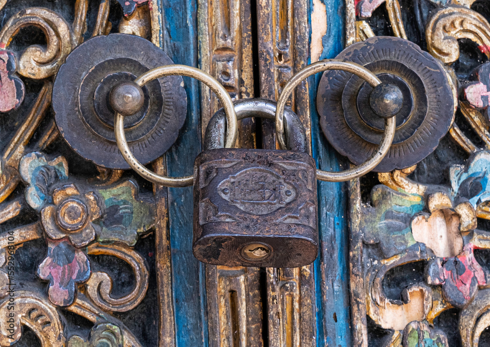 Close up antique black iron ring knobs and padlock on wooden carved door Close up antique black iron ring knobs and padlock on wooden carved door