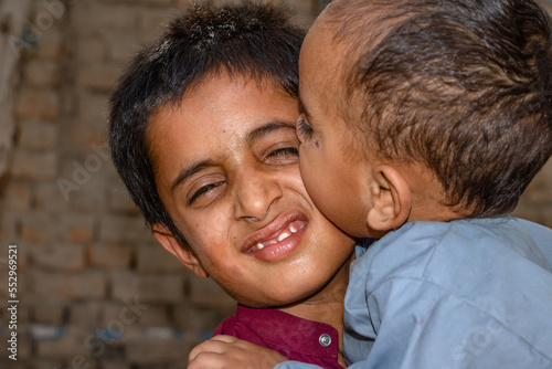 a young boy is carrying his little brother and smiling  photo