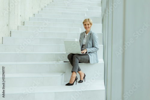 Businesswoman using laptop computer on modern office stairs