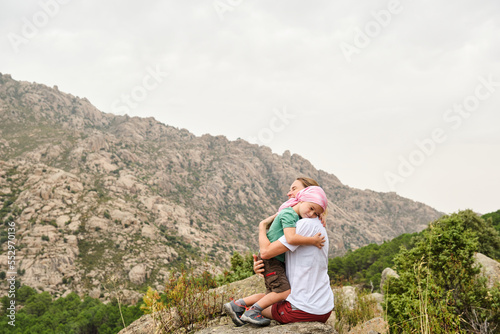 Child with cancer hugging his mother in nature. He wears a pink scarf on his head