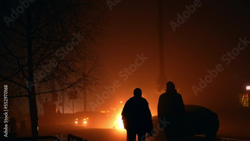 Silhouettes of people in the lights of car lamps outdoors. Blackout in Ukraine during war. Ukrainians moving by the city streets at night. photo