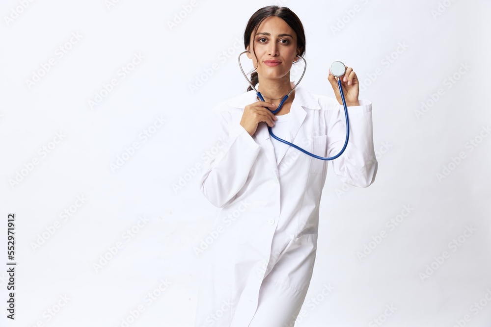 Woman doctor with stethoscope in hand in medical gown on white nurse background, consequences of covid-19, noise in lungs, concept of health and science Woman doctor with stethoscope in hand in medical gown on white nurse background, consequences of covid-19, noise in lungs, concept of health and science