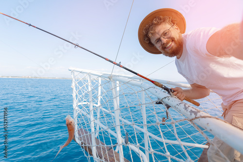 Tourist Fisherman on Tour fishing, man hold fish red mullet on boat in sea sunset light photo