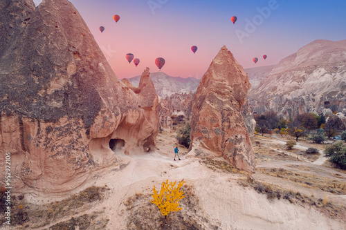 Young hiker man in hat on top mountain background hot air balloons and Cave house in Cappadocia Turkey travel, aerial top view