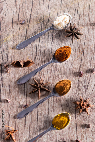 Almonds, cinnamon, paprika and turmeric powder in a spoon on a rustic wooden table.