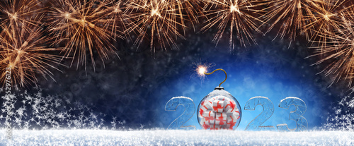 NNew Year card with ice number 2023. Christmas tree toy in the form of a ball with gifts in the form of a bomb. Festive banner with salutes against the background of night abstract defocused lights. photo