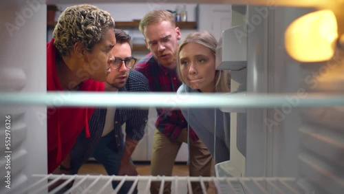 Hungry multiethnic friends open empty fridge. Realtime