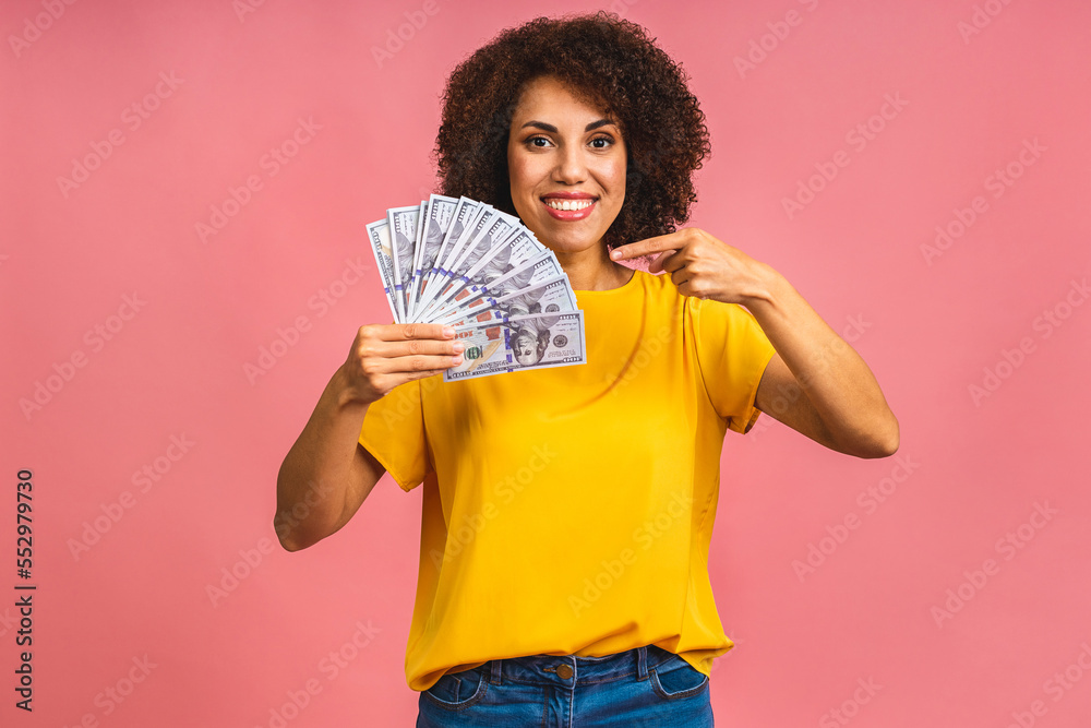 Happy winner. Portrait of african american successful woman 20s with afro hairstyle holding lots of money dollar banknotes isolated over pink background. Happy winner. Portrait of african american successful woman 20s with afro hairstyle holding lots of money dollar banknotes isolated over pink background.