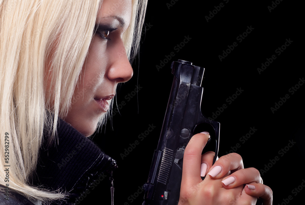 Young woman shooting with gun isolated on black background