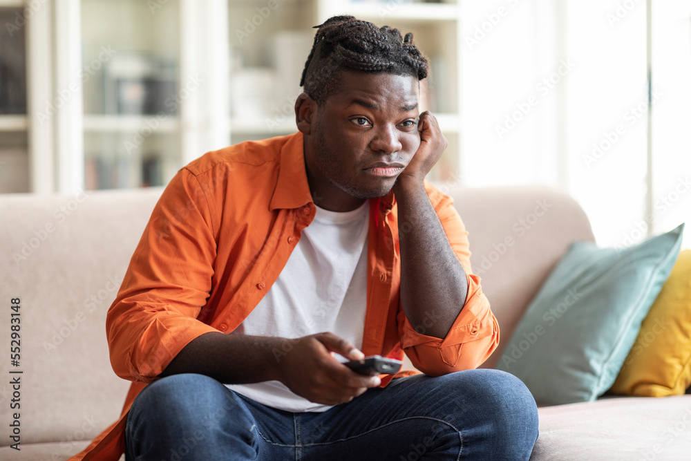 Boring african american guy sitting at home, switching tv Boring african american guy sitting at home, switching tv
