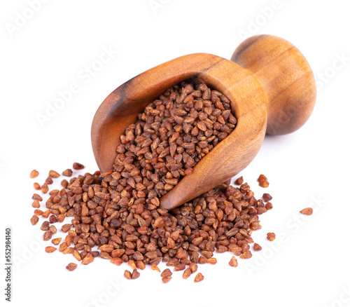 Buckwheat tea in wooden scoop, isolated on white background. Whole roasted buckwheat grains. Fagopyrum tataricum.