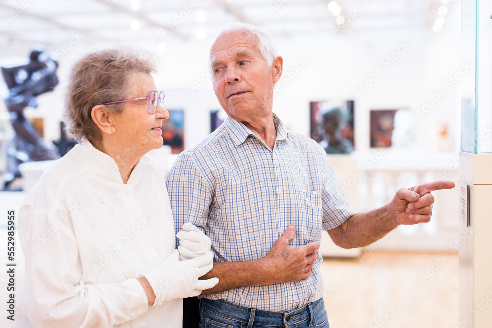 Fototapeta premium mature European couple examines paintings in an exhibition in hall of art museum
