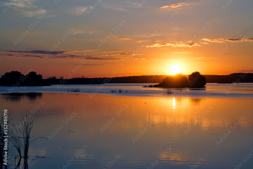 Quiet evening over the lake. Bright sunset and ducks on the water surface. Summer.	