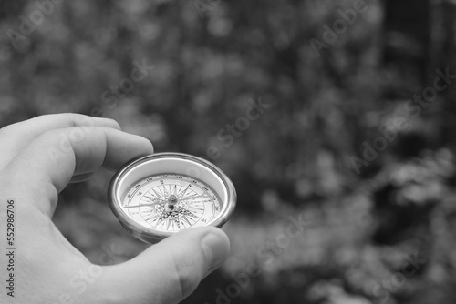 Old classic navigation compass in hand on natural background