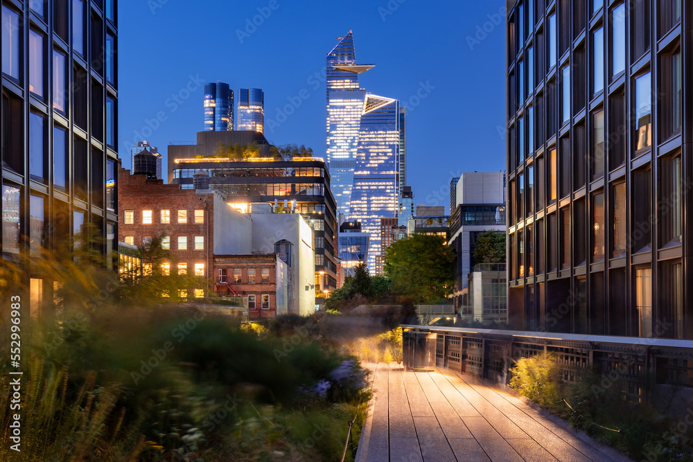 New York City Highline promenade in Chelsea. Elevated greenway with Hudson Yards skyscrapers in evening. Manhattan