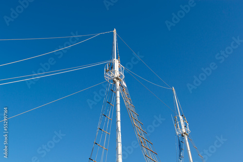 Sailboat ship mast on clear blue sky background, viewed from below