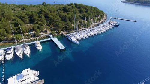 Aerial view beautiful bay of a Croatian island in the mediterranean sea, many identical white yachts at the pier on a sunny summer day