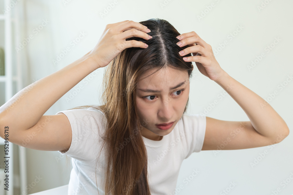 Damaged hair, face serious asian young woman, girl worry looking at scalp in mirror, hand in break into front hair loss, thin problem symptom from shampoo at home. Health care of beauty concept. Damaged hair, face serious asian young woman, girl worry looking at scalp in mirror, hand in break into front hair loss, thin problem symptom from shampoo at home. Health care of beauty concept.
