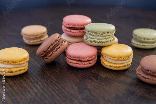 randomly arranged fresh and colorful macarons on dark wooden table, gluten free