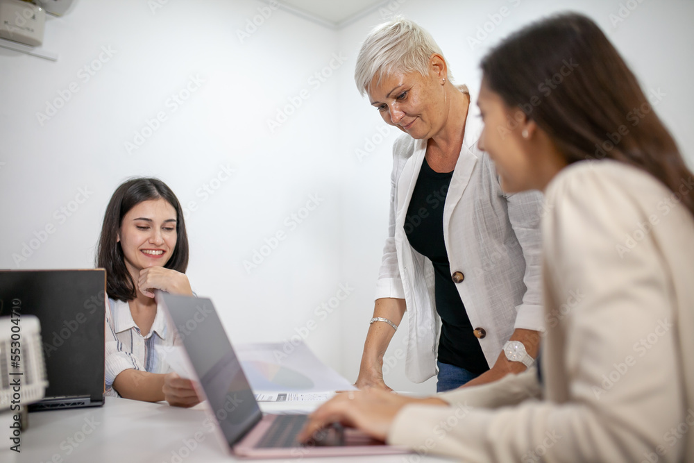 business team female colleagues talking at work share ideas with laptop, Happy colleagues work together, CEO executive in corporate office. business team female colleagues talking at work share ideas with laptop, Happy colleagues work together, CEO executive in corporate office.