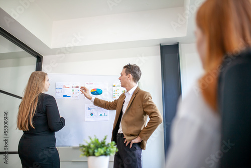 business team male and female colleagues talking at work share ideas with chart on board, Happy young presentation colleagues work together on board.