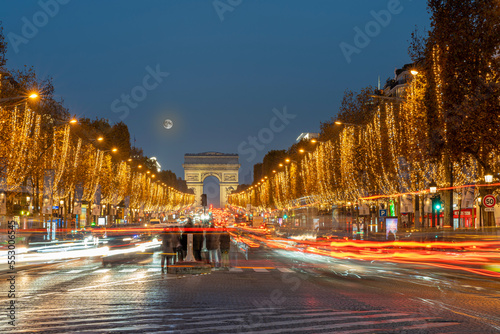Paris - France,France - 12 08 2022: View of the Arc-De-Triomphe and Avenue des Champs Elysees with Christmas lights and full moon