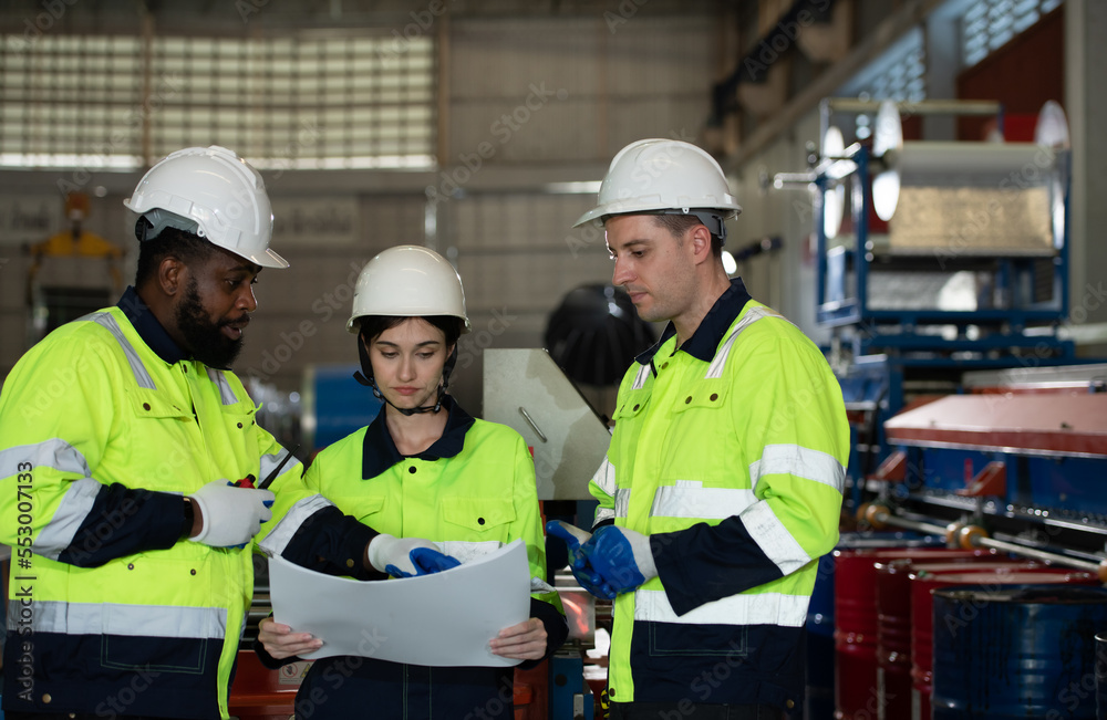 Young female engineer learning to run machinery at a factory with veteran engineers Young female engineer learning to run machinery at a factory with veteran engineers