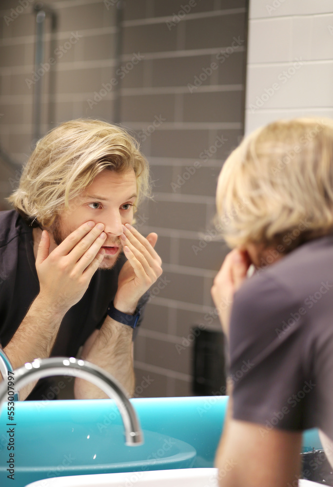 young man looking in the mirror,combing his hair,looking at problems on face. young man looking in the mirror,combing his hair,looking at problems on face.
