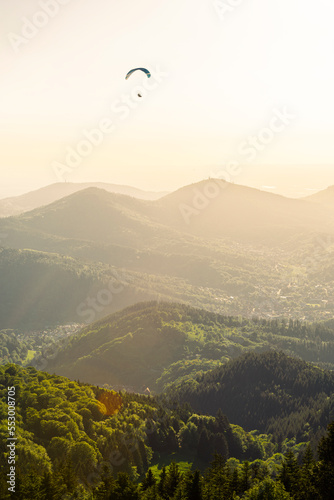 Ein Gleitschirmflieger an der Teufelsmühle im Schwarzwald vor dem Panorama von Murgtal, Rheintal und Vogesen in der Abendsonne, Baden-Württemberg, Deutschland